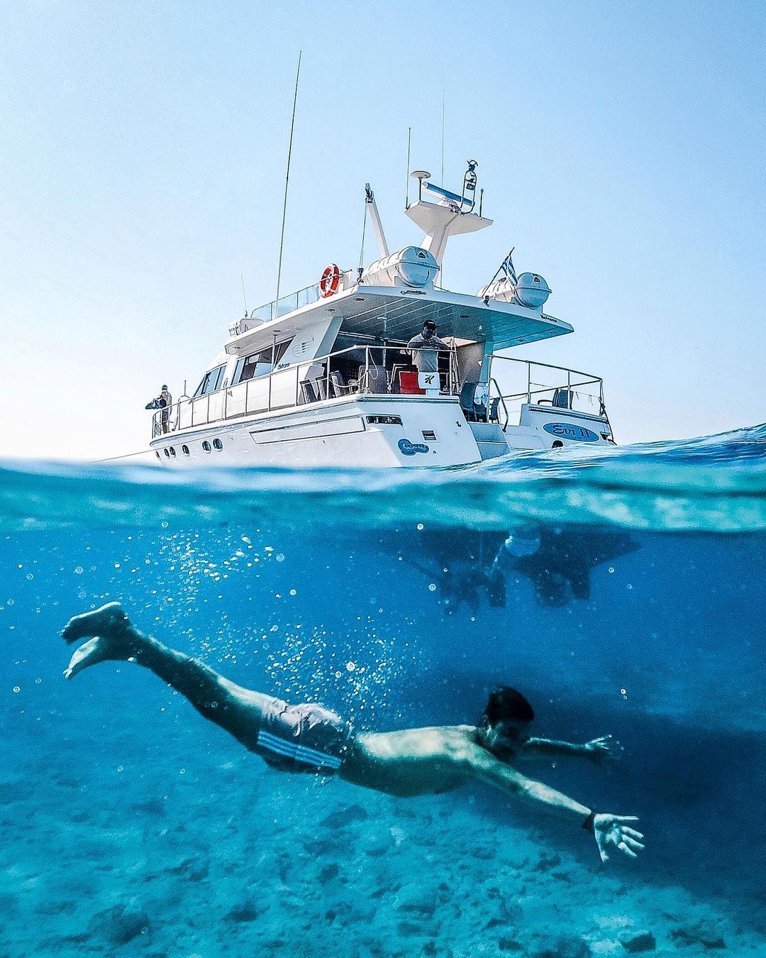 Swimmer underwater beneath a boat off Ierapetra in southeast Crete